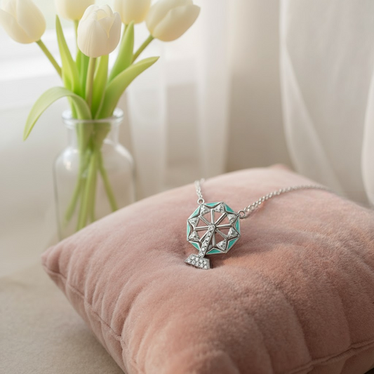 Necklace with a decorative pendant on a pink cushion next to a vase of white tulips.