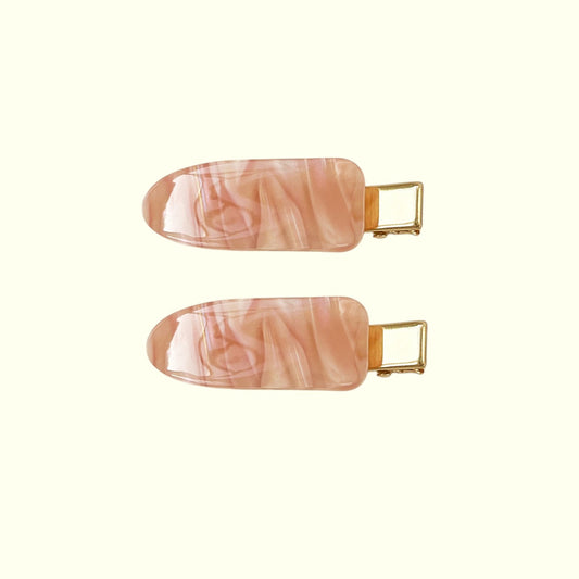 Two pink marbled hair clips with gold hardware on a white background