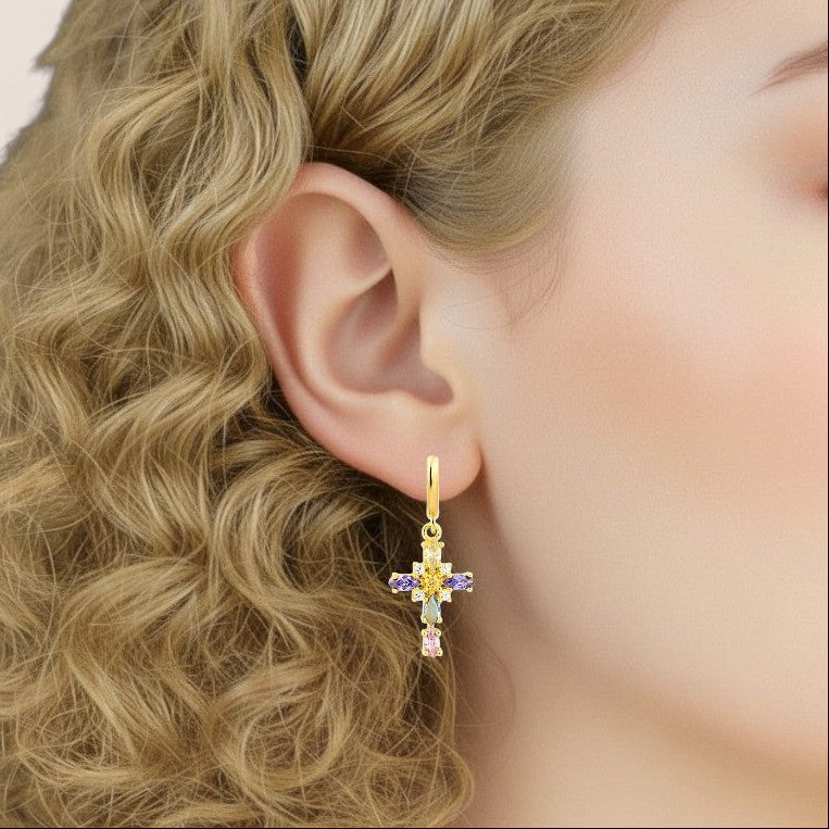 Close-up of a person wearing a gold earring with colorful stones.