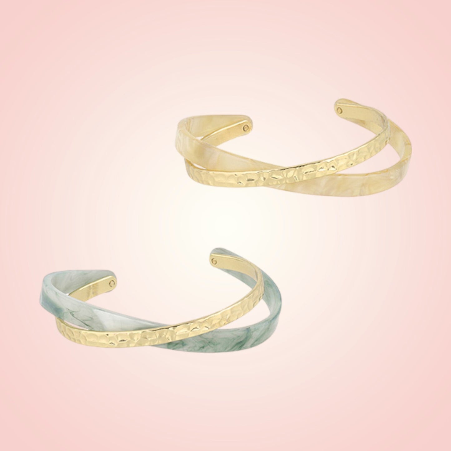 Two gold and green marble patterned cuffs on a gradient pink background
