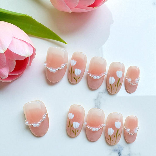 Nail art with floral designs on a marble surface with pink flowers.