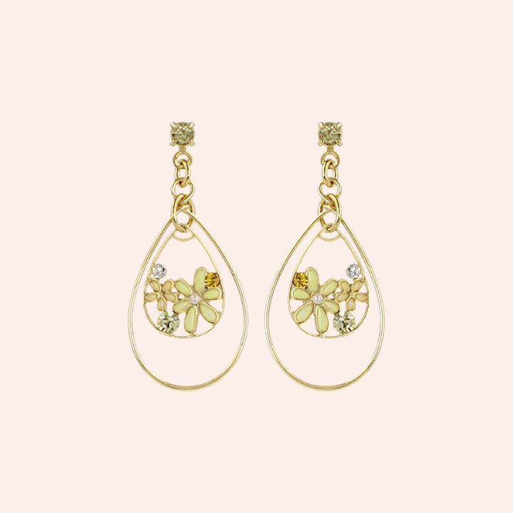 Gold teardrop earrings with floral designs on a light pink background