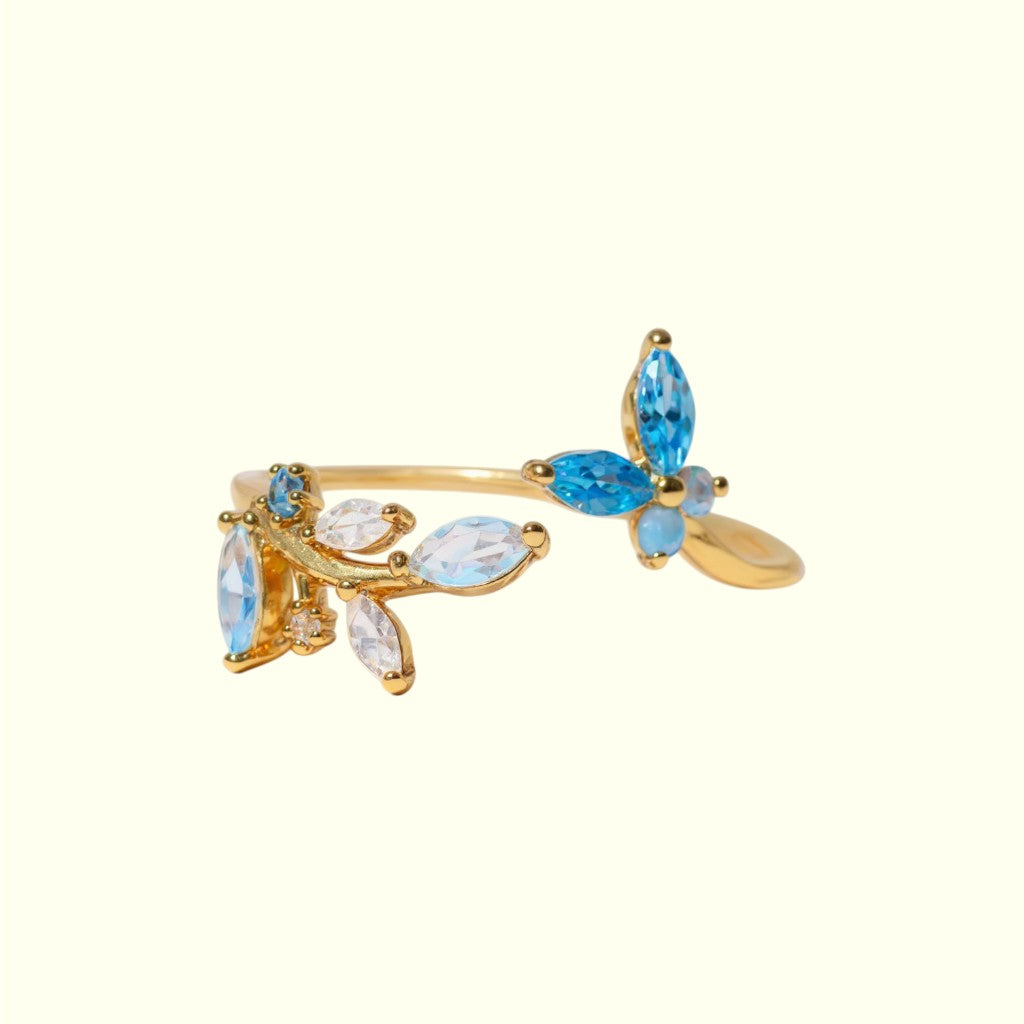 Gold ring with blue and clear gemstones on a white background