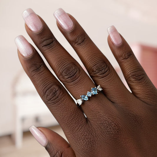 Hand wearing a silver ring with blue gemstones on a blurred background