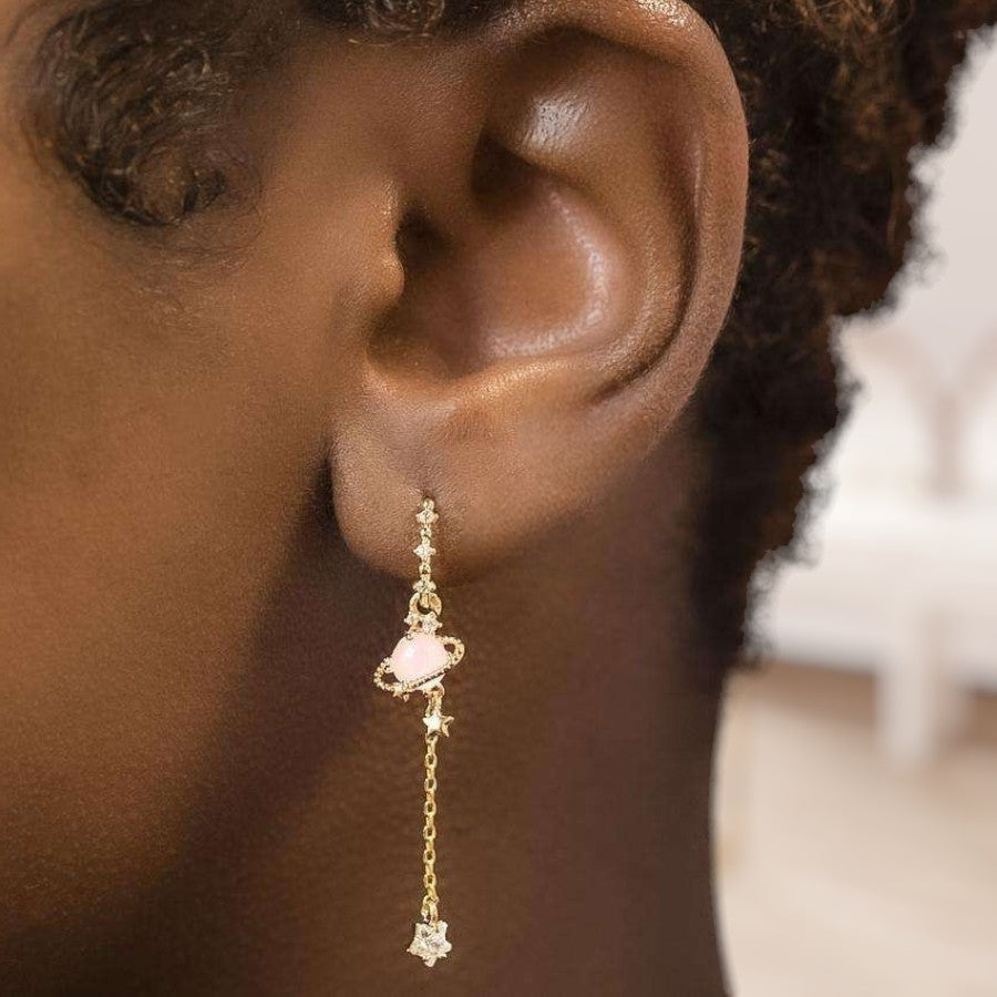 Close-up of an ear wearing a gold earring with a pink gemstone.
