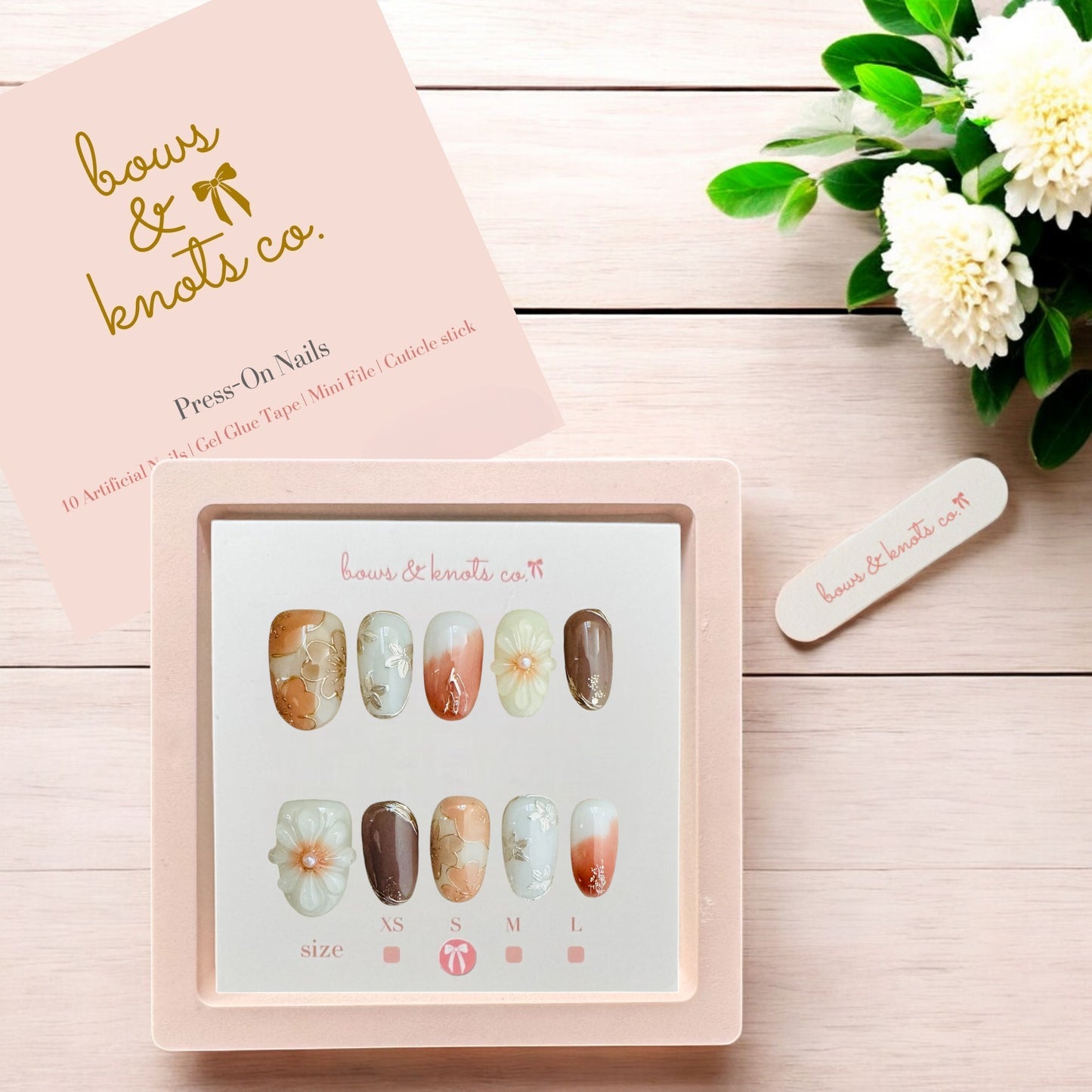 Press-on nails set with a pink box on a wooden surface, featuring the brand 'bows & knots co'.