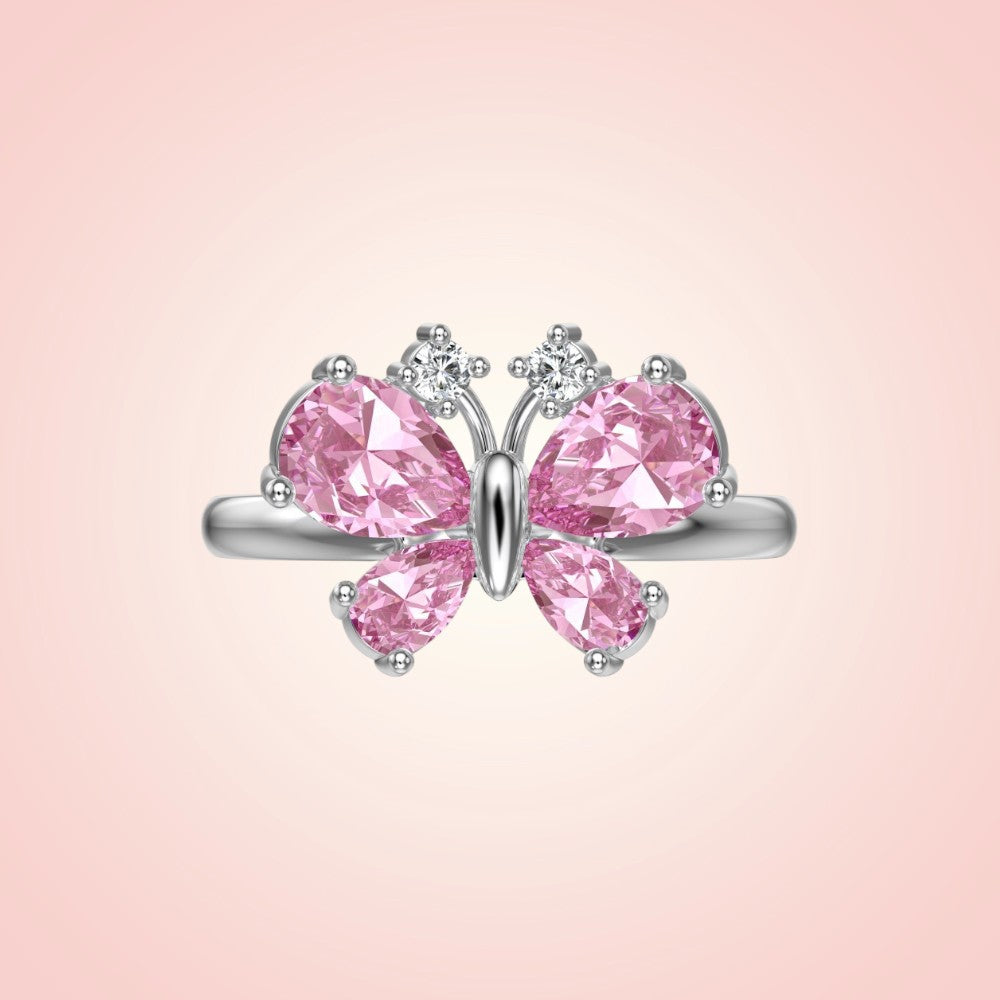 Butterfly-shaped ring with pink gemstones on a pink background