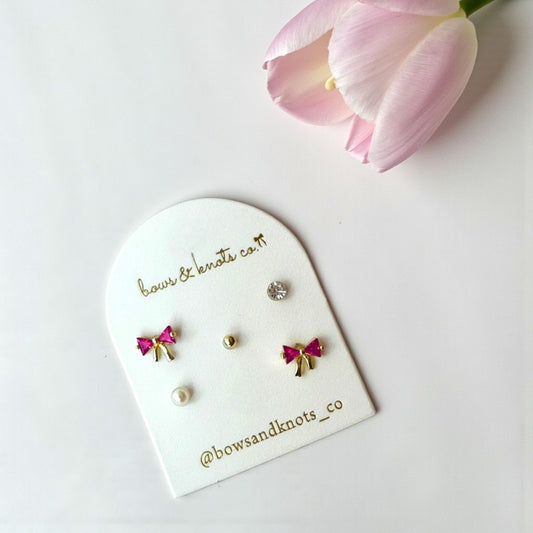 Set of earrings on a 'bows & knots co' branded card with a pink tulip in the background.