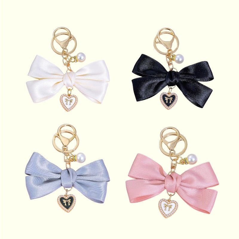 Four colorful bow keychains with heart charms on a white background