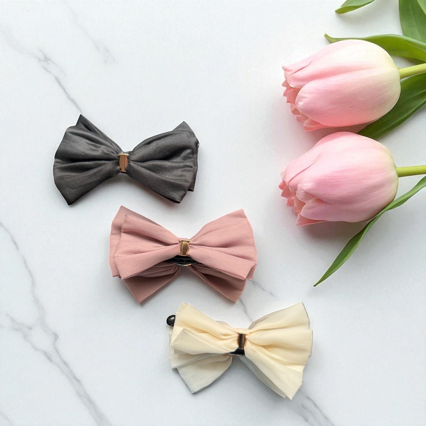 Three bow clips in gray, pink, and beige with pink tulips on a white background