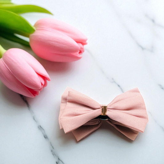Pink bow hair clip on a marble surface with pink tulips