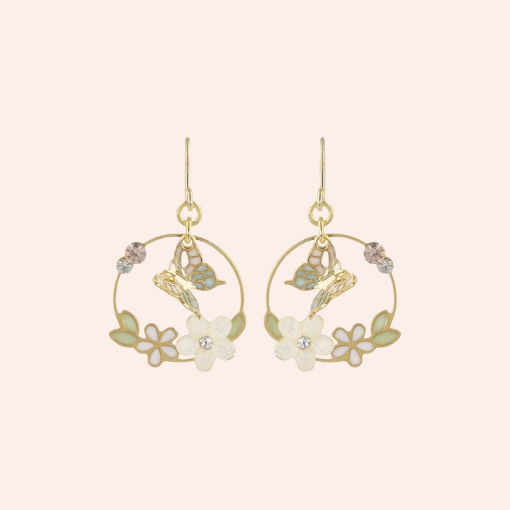 Gold hoop earrings with floral and butterfly designs on a light pink background