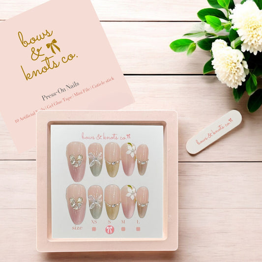Press-on nails set with packaging and floral decoration on a wooden surface