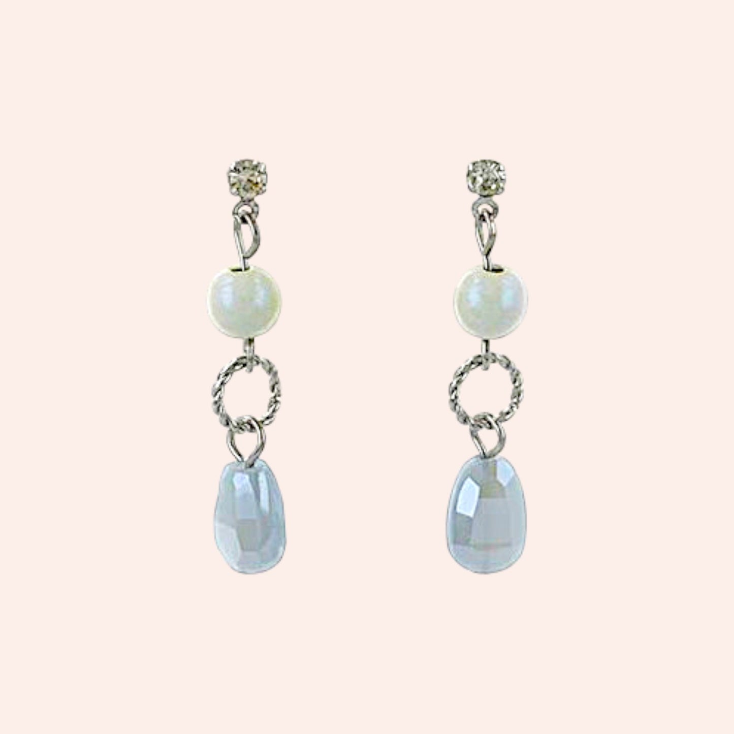Pair of earrings with pearl and gemstone drops on a light pink background