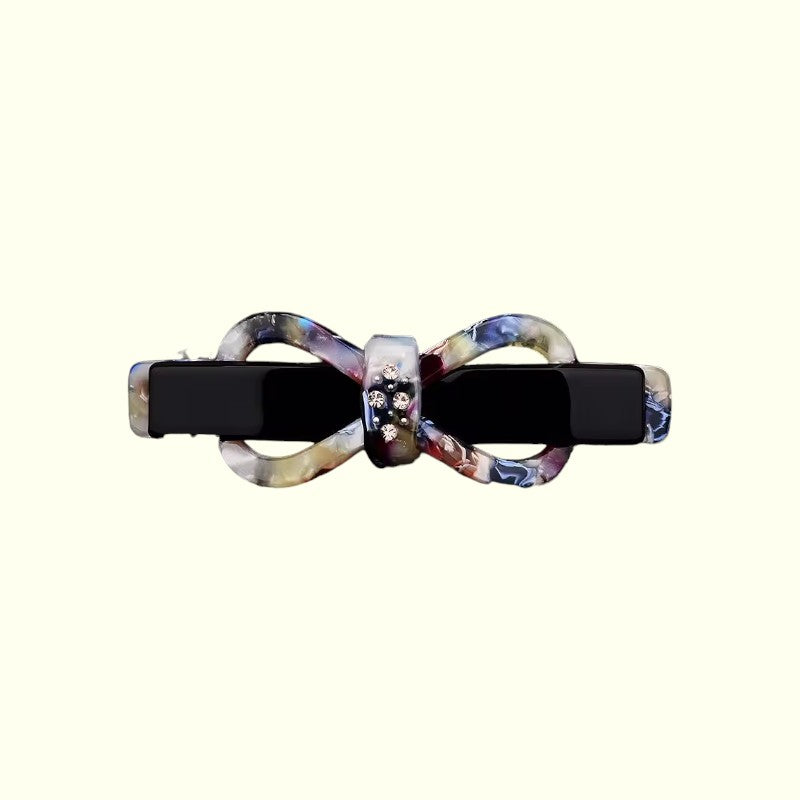Bow-shaped hair clip with black center and multicolored bow on a white background