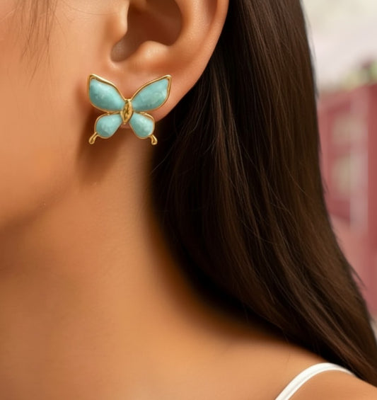 Butterfly-shaped earrings worn by a person with blurred background