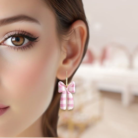 Close-up of a woman wearing a pink checkered bow earring with a blurred background