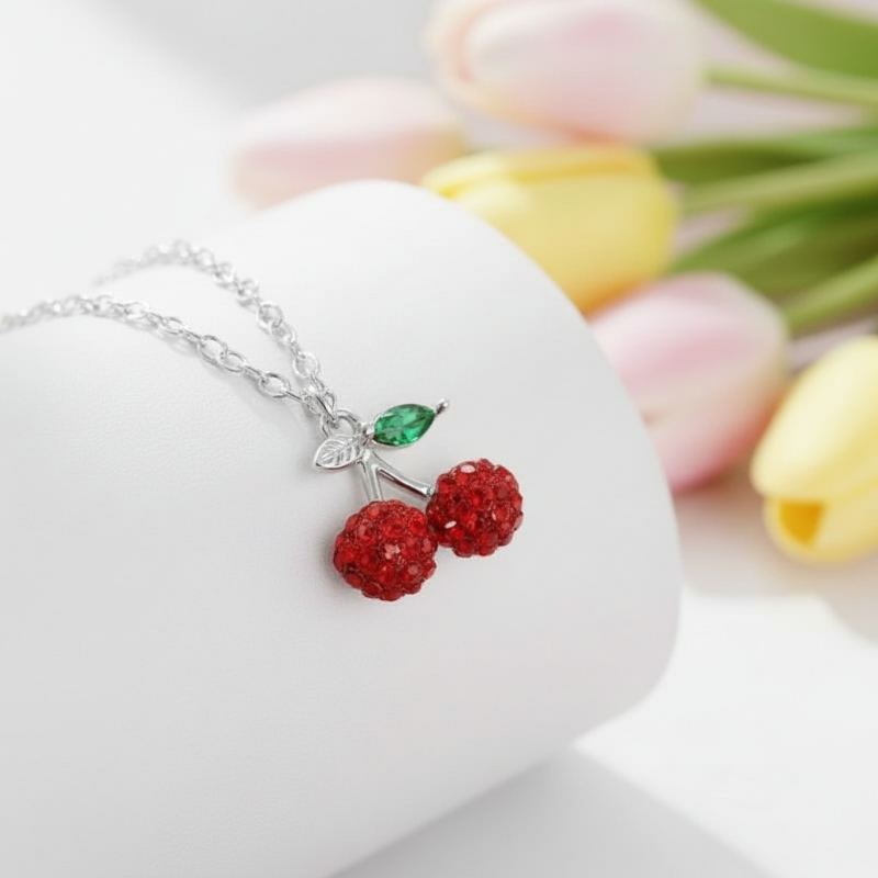 Necklace with cherry pendant on a white stand with tulips in the background