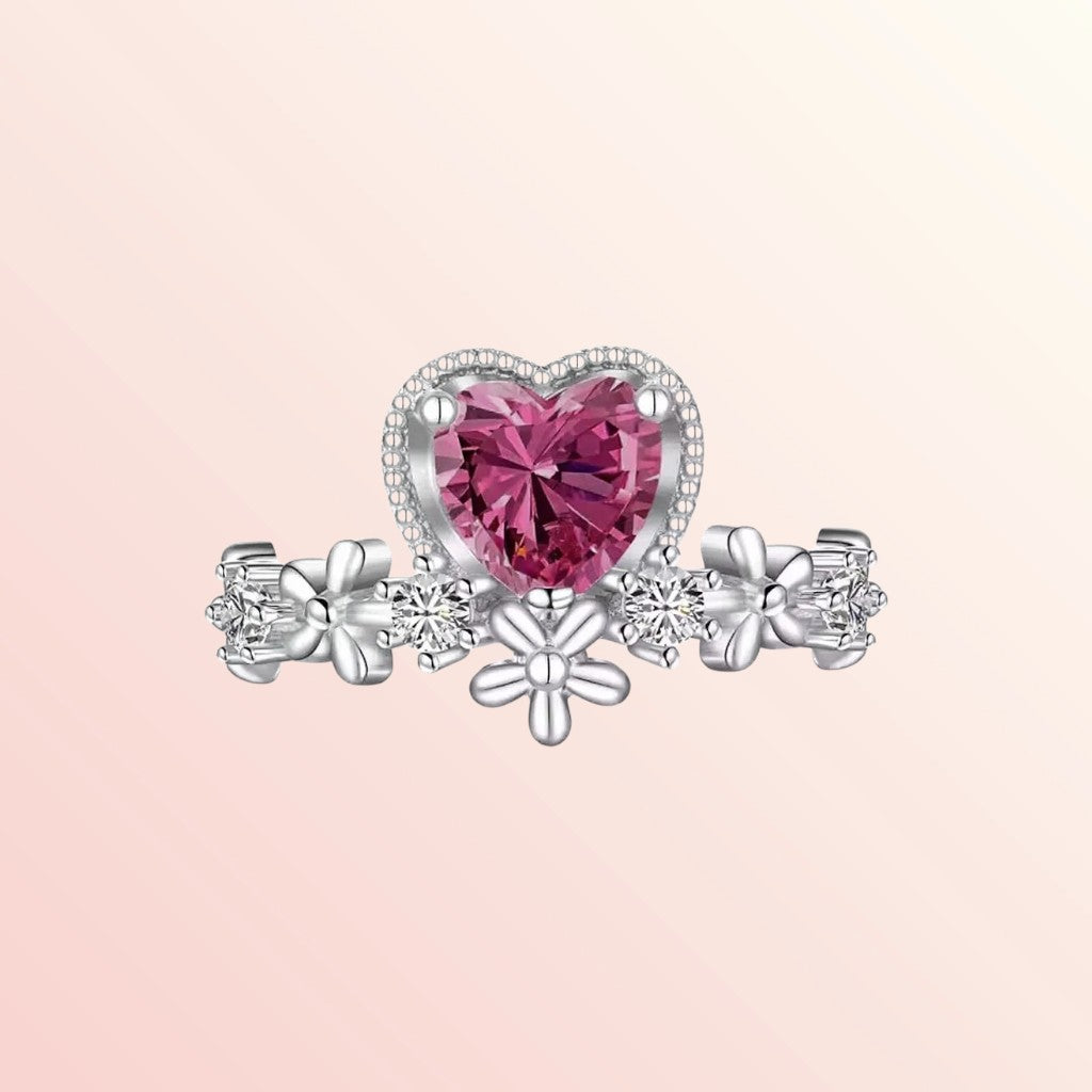Silver ring with a pink heart-shaped gemstone on a light pink background
