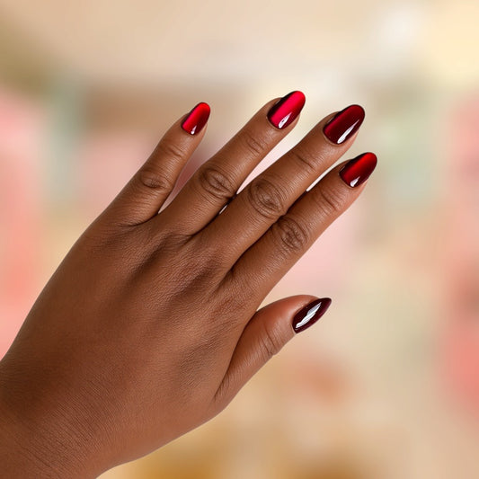 Close-up of Crimson Muse handmade press-on nails featuring glossy deep burgundy red and vibrant ruby pink ombré accents on elegant almond-shaped nails, modeled on a hand by Bows and Knots Co.
