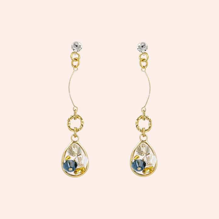 Gold earrings with teardrop-shaped clear stones and blue accents on a white background