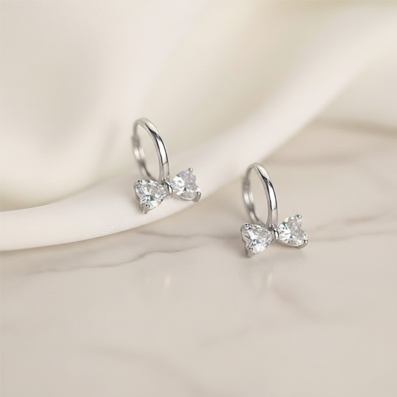 Pair of silver heart-shaped earrings on a soft beige background