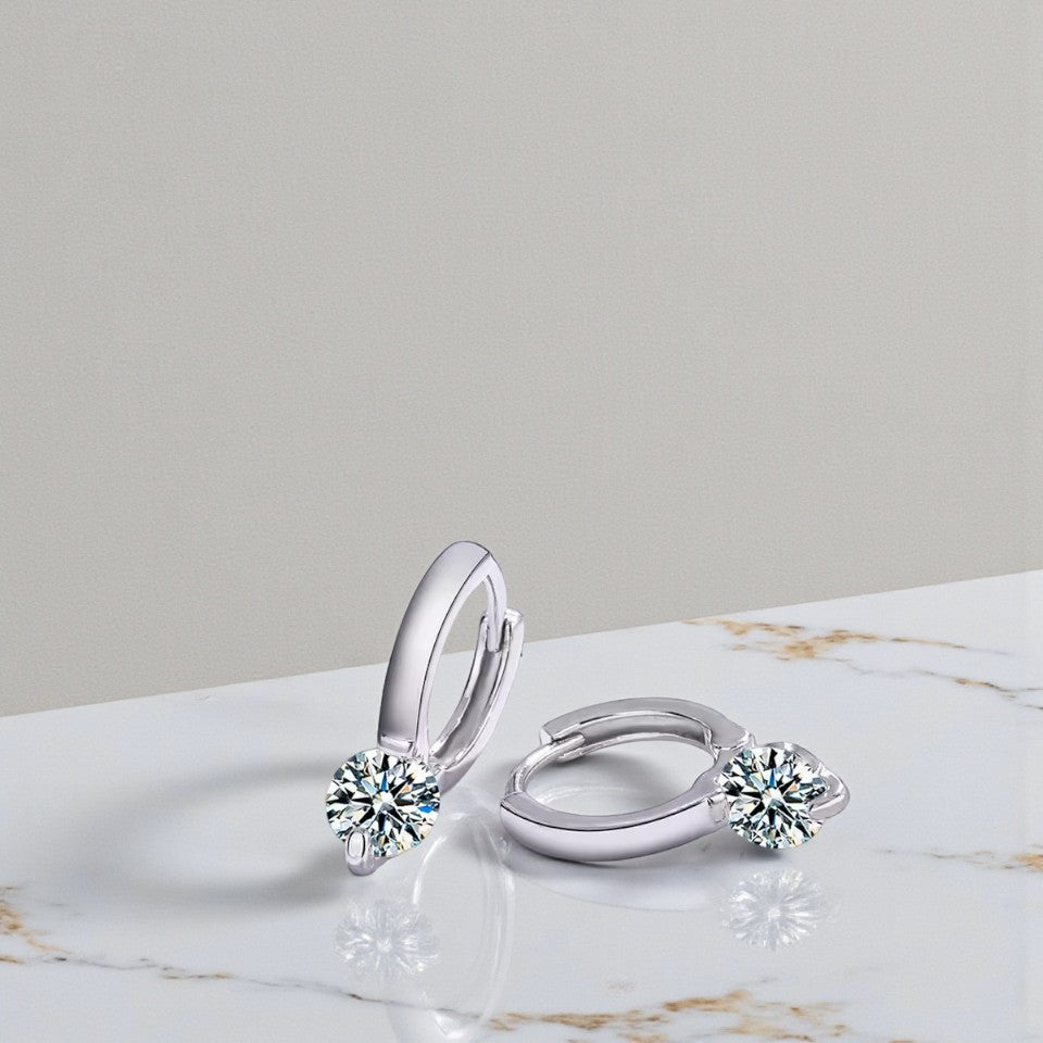 Silver hoop earrings with gemstones on a marble surface