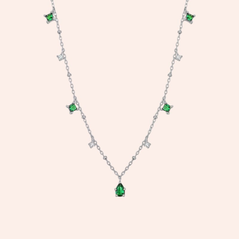 Necklace with green gemstones on a light pink background