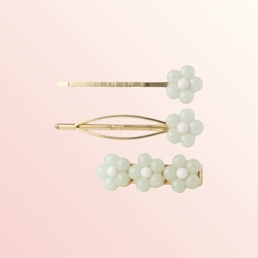 Set of three floral hair pins with gold accents on a light pink background
