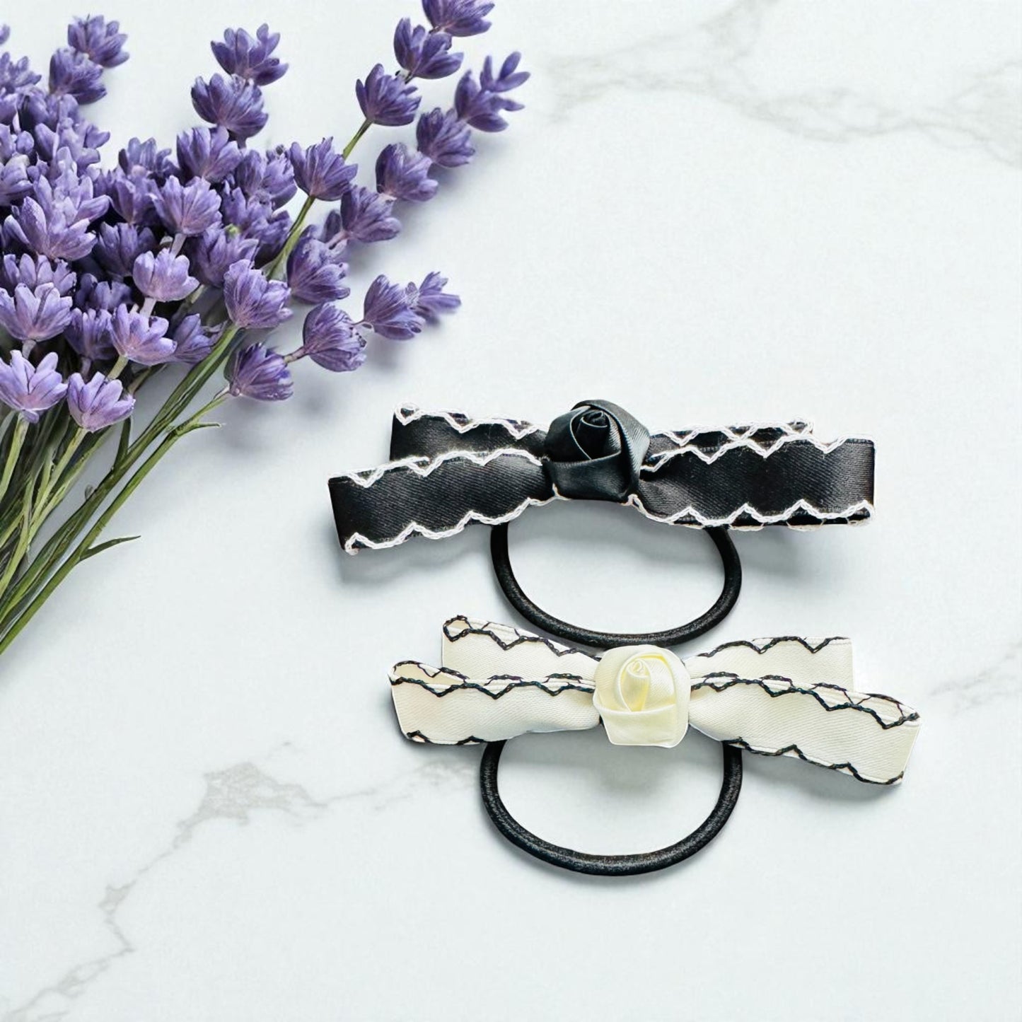 Two decorative hair ties with floral designs on a marble surface with lavender flowers.