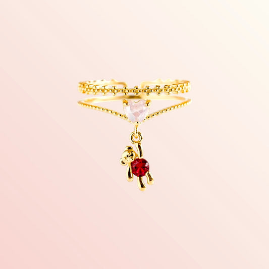 Gold ring with a small red gemstone on a beige background