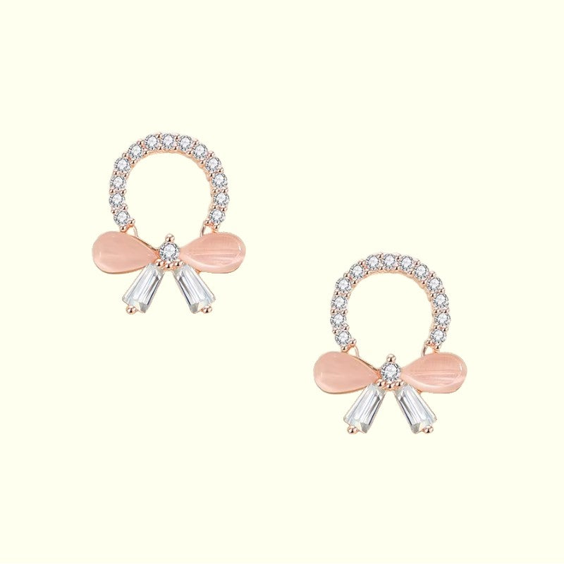 Pair of earrings with pink bows and clear gemstones on a white background