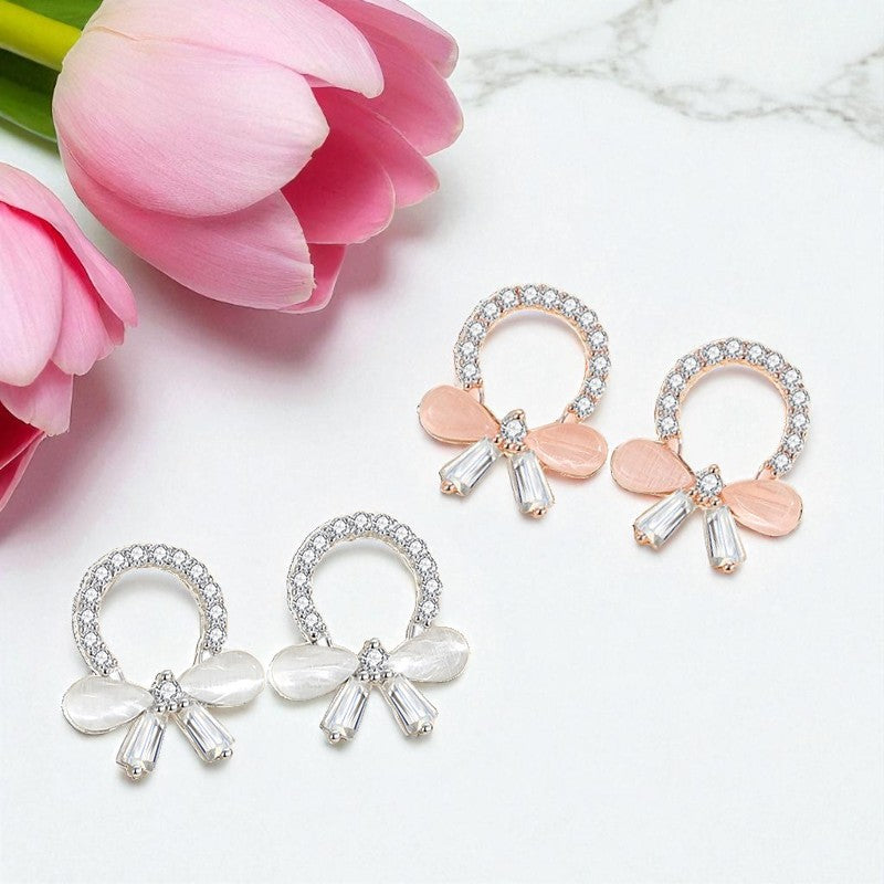 Pair of bow-shaped earrings with pink flowers on a marble surface