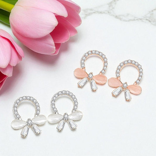 Pair of bow-shaped earrings with pink flowers on a marble surface