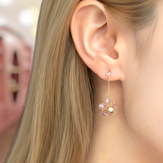 Close-up of an ear wearing a floral earring with pink and purple stones.