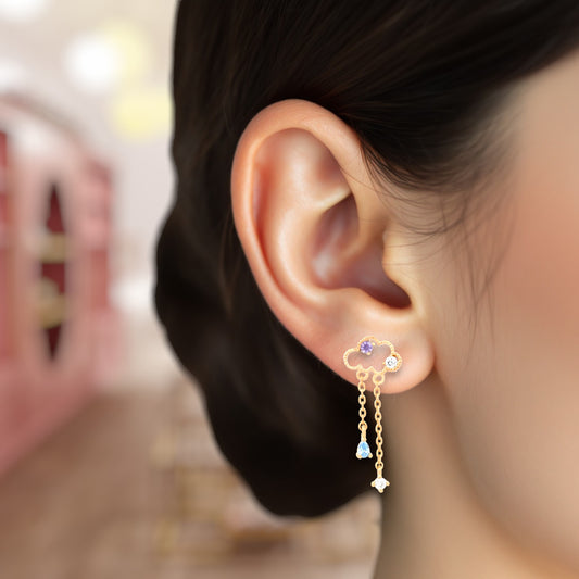 Close-up of an ear wearing a gold earring with colorful stones.