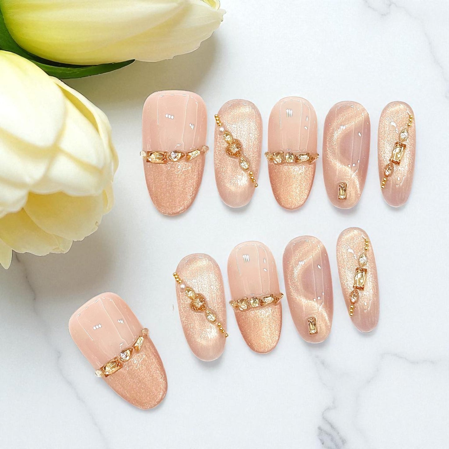 Nail art with gold accents on a white surface with yellow flowers.