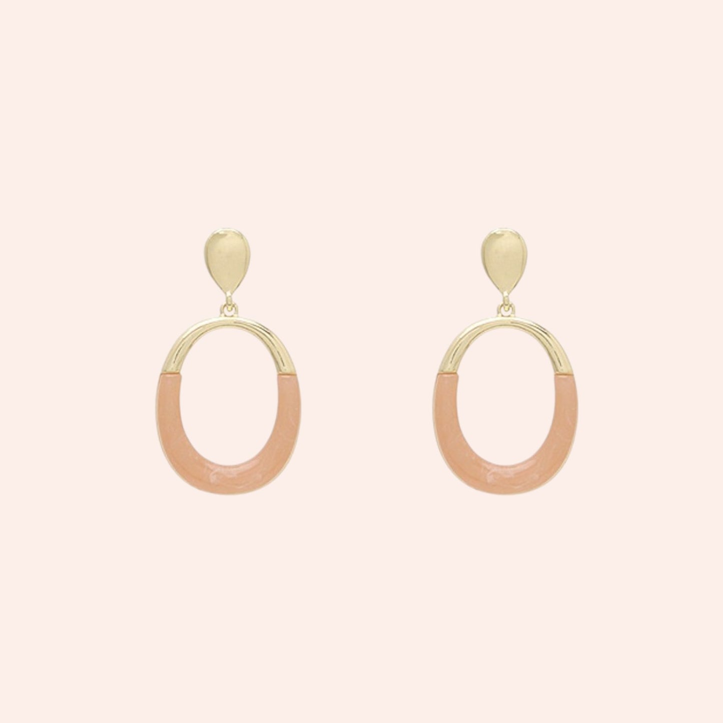 Pair of gold and pink hoop earrings on a light pink background