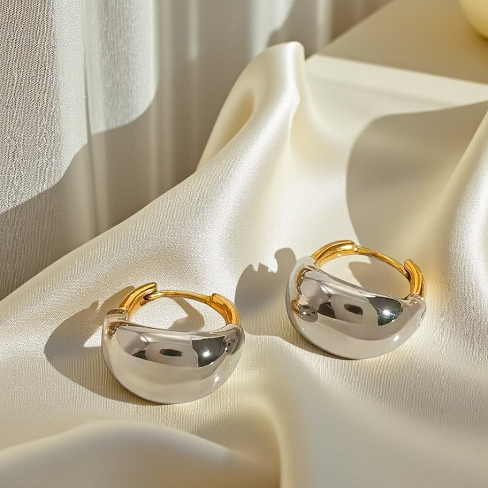 Pair of gold and silver hoop earrings on a soft fabric surface