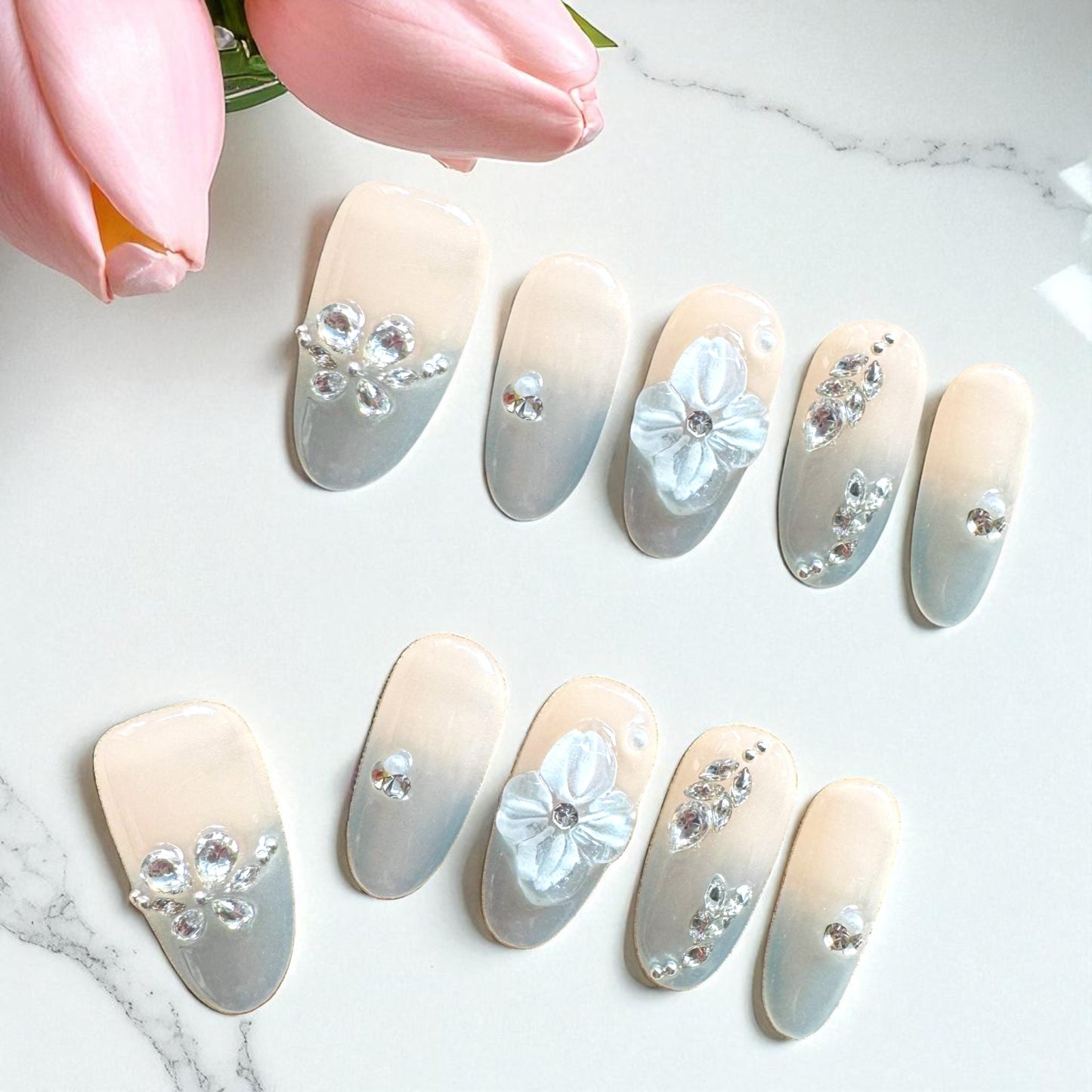 Decorative nail art with flowers and crystals on a marble surface
