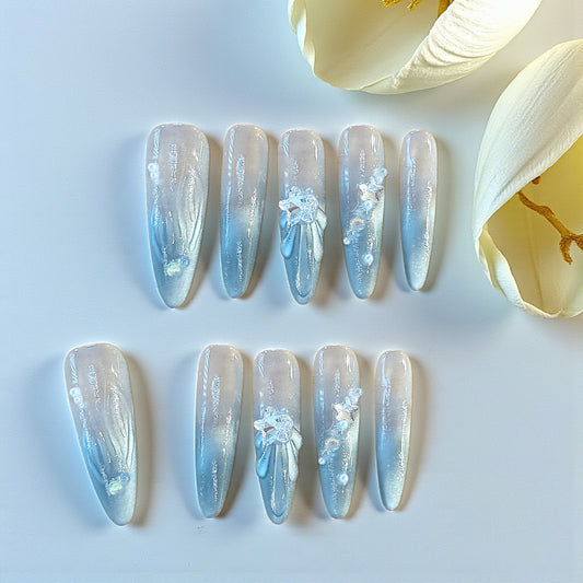 Set of decorative nail extensions with floral designs on a light blue background.