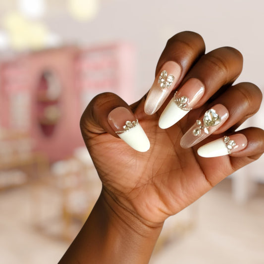 Hand with white nails and decorative crystals, blurred background