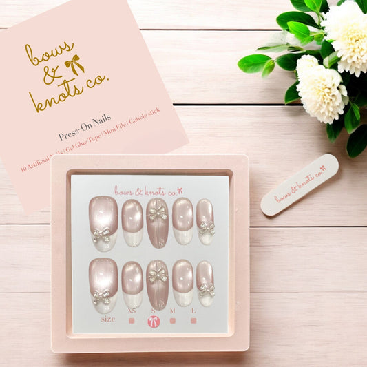 Press-on nails set with a pink box on a wooden surface, featuring the brand 'bows & knots co'.