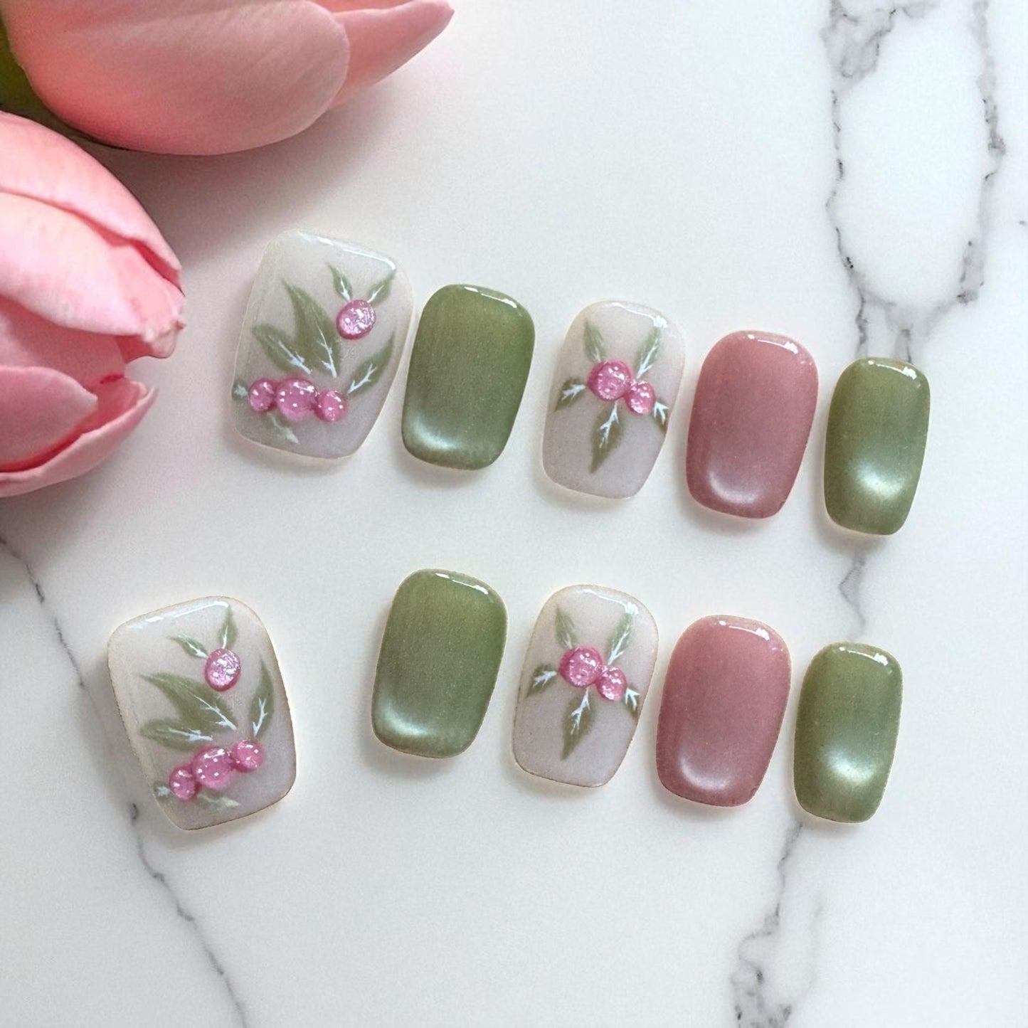 Nail art with floral designs on a marble surface with pink tulips.