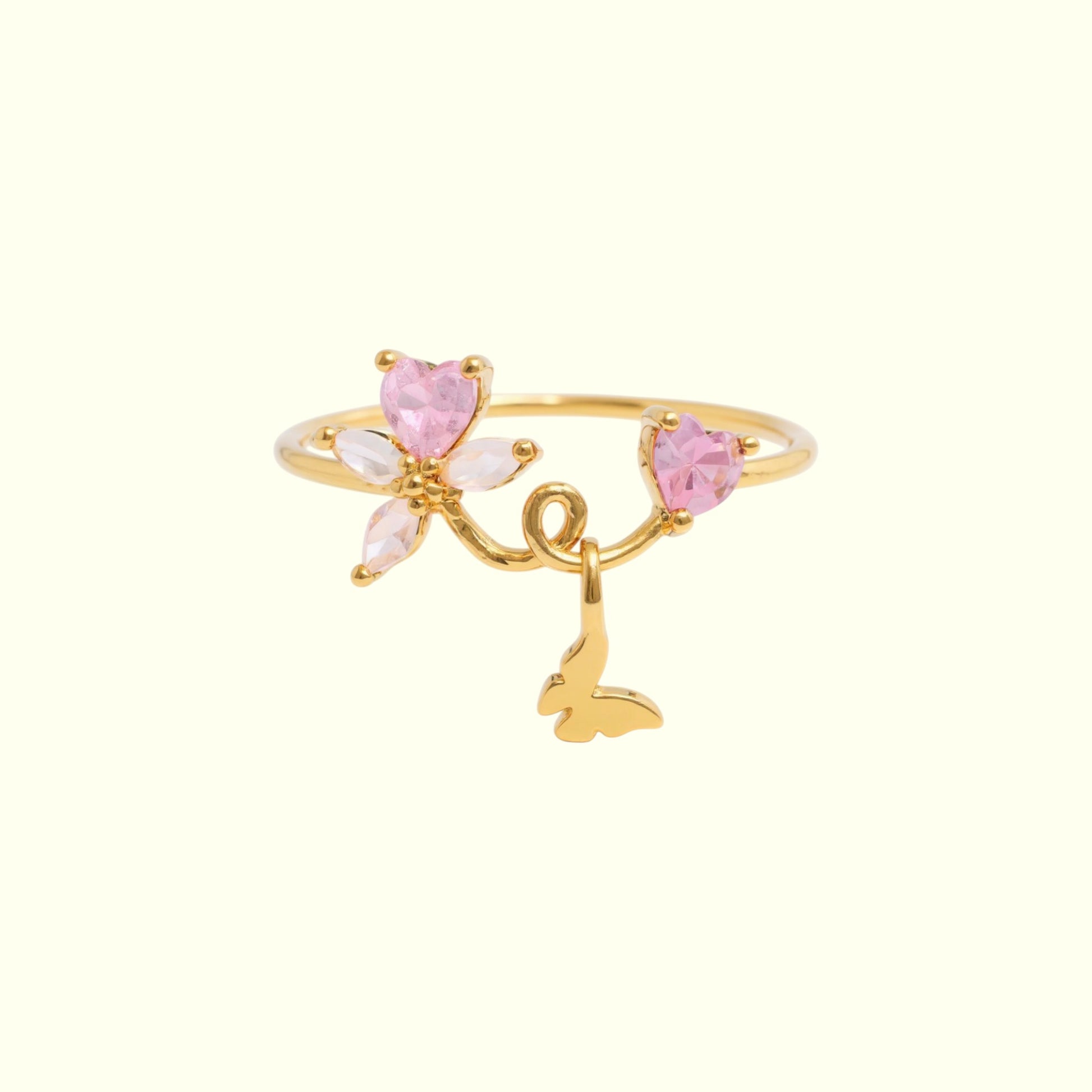 Gold ring with pink heart-shaped stones and a butterfly charm on a white background