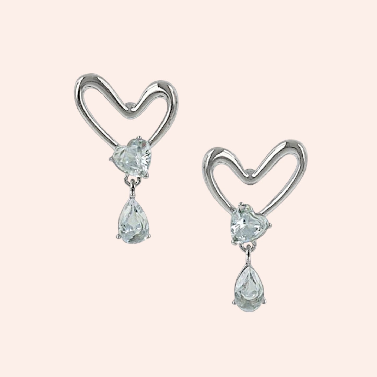 Heart-shaped earrings with teardrop-shaped gemstones on a light pink background