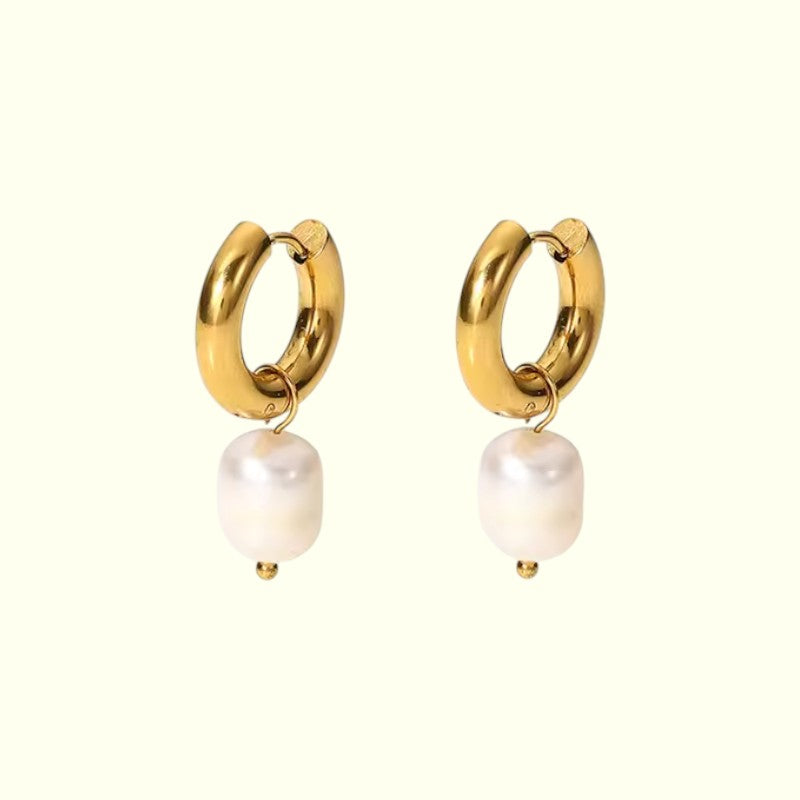 Gold hoop earrings with white pearls on a white background