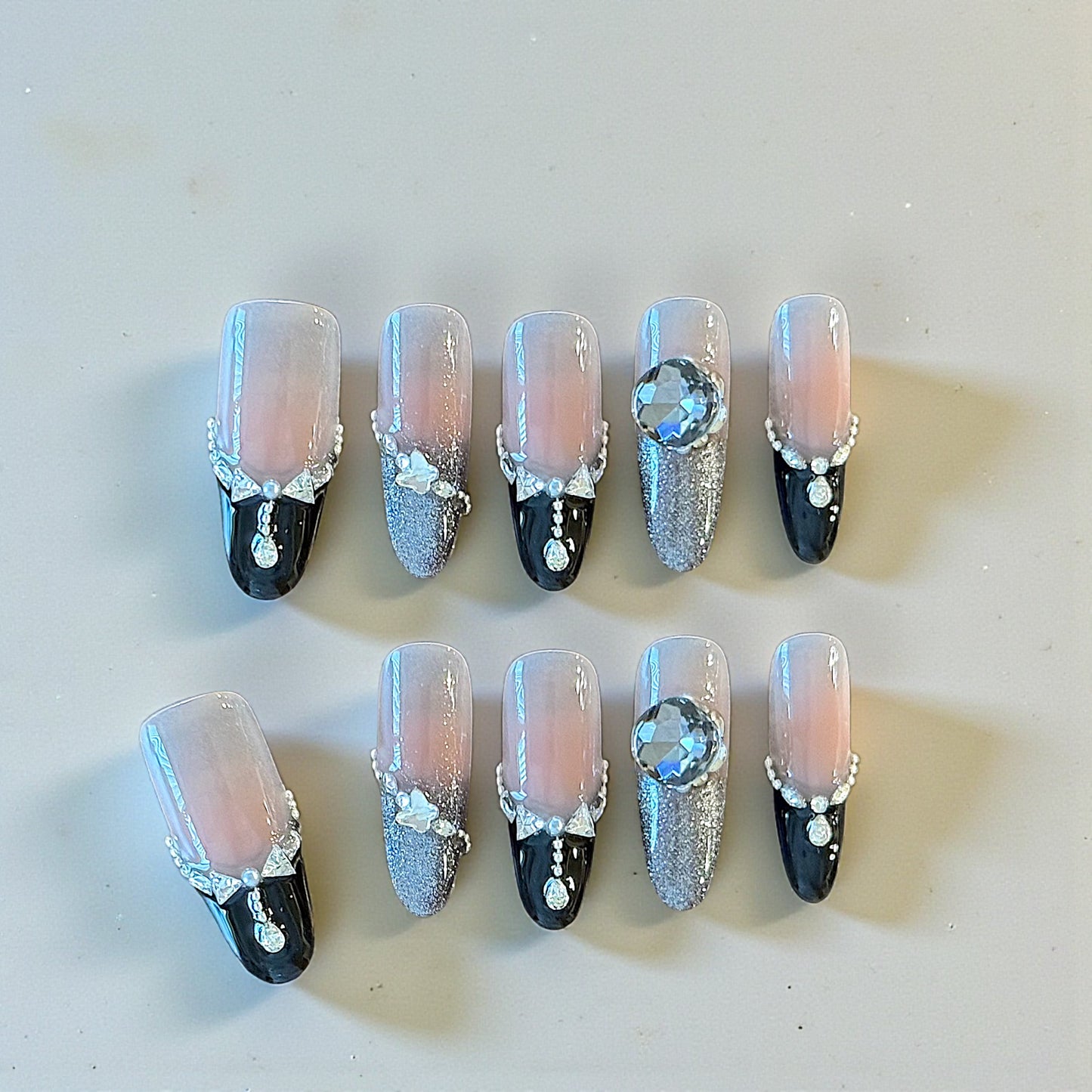 Decorative nails with black, silver, and clear designs on a light background