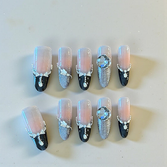 Decorative nails with black, silver, and clear designs on a light background