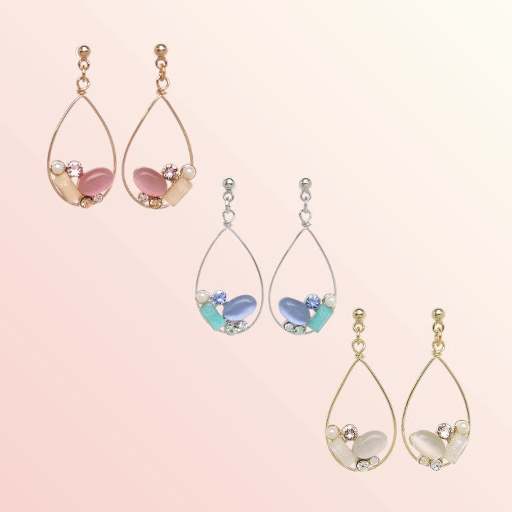 Set of teardrop-shaped earrings with gemstone-like beads on a light pink background